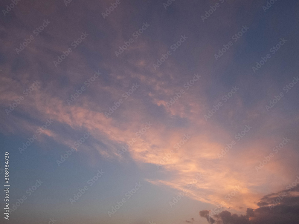 Bright multicolored clouds enlightened with rays of setting sun. Bright evening sky with pink, blue and purple cumulus, stratus and cirrus clouds