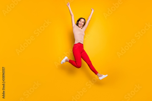 Full body photo of cheerful girl hear win lottery news jump scream yeah raise fists wear casual style clothing isolated over yellow color background