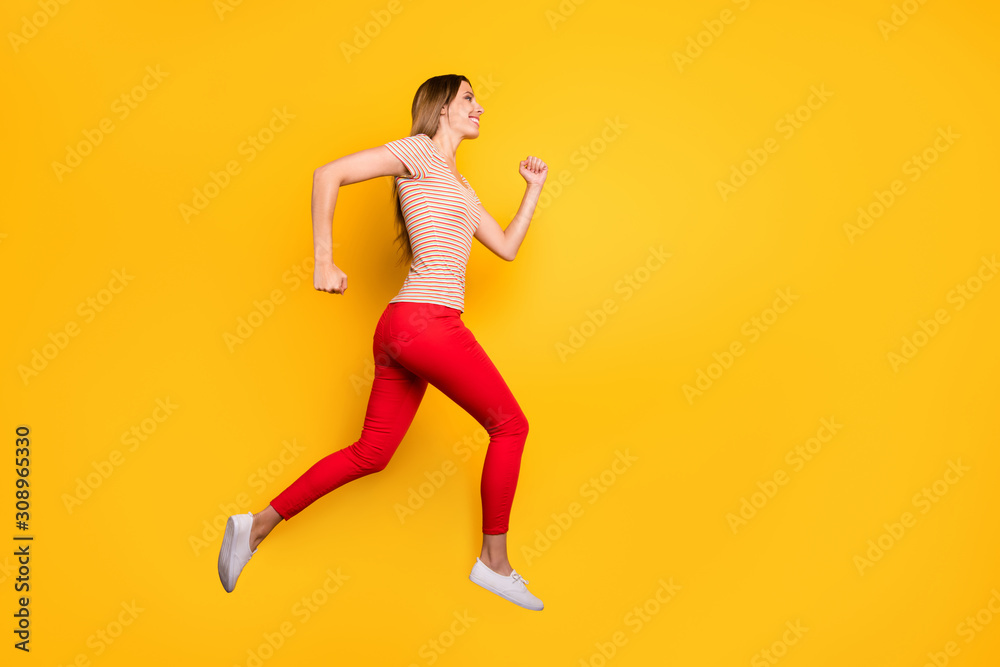 Full length profile photo of funky lady jumping high rushing discount shopping store addicted person wear casual striped t-shirt red trousers isolated yellow color background