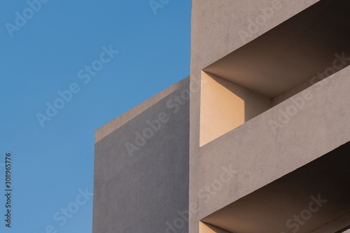 part of the white facade of the building with windows and balconies against a clear blue sky at sunrise and sunset