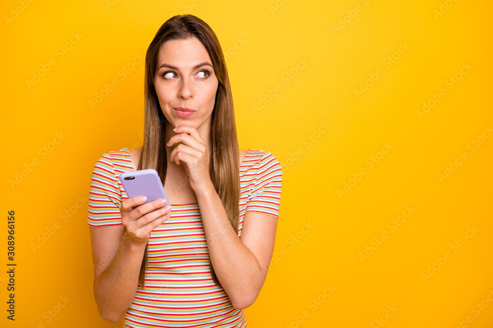 Photo of pretty clever lady hold telephone hands thinking over new instagram post text idea creative person hand on chin wear casual striped t-shirt isolated yellow color background Photo of pretty clever lady hold telephone hands thinking over new instagram post text idea creative person hand on chin wear casual striped t-shirt isolated yellow color background