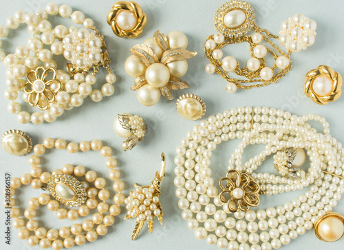 Pearls background. Woman's Jewelry. Vintage jewelry background. Beautiful gold tone and pearls brooches, braceletes, necklaces and earrings on blue background. Flat lay, top view.