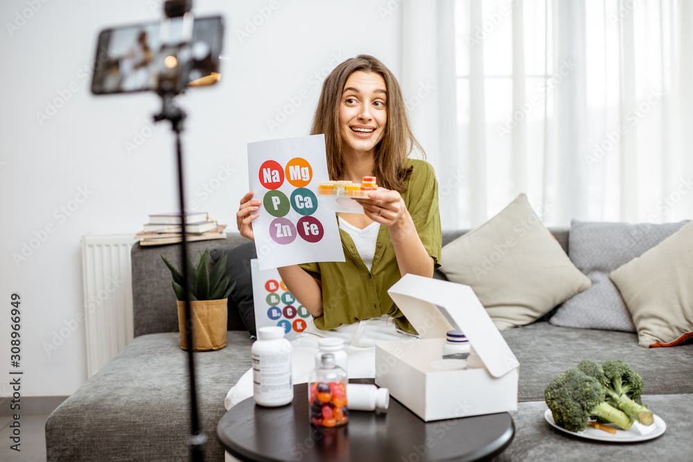 Young woman recording on a smart phone her vlog about healthy eating and nutritional supplements. Preventive medicine and influencer marketing concept Young woman recording on a smart phone her vlog about healthy eating and nutritional supplements. Preventive medicine and influencer marketing concept