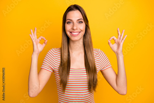 Closeup photo of amazing lady showing okey symbols toothy beaming smiling express positive attitude wear casual striped t-shirt isolated yellow color background