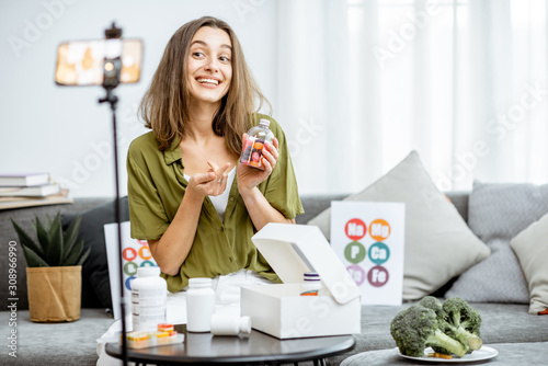 Young woman recording on a smart phone her vlog about healthy eating and nutritional supplements. Preventive medicine and influencer marketing concept photo