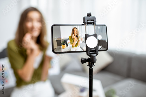 Young woman recording her vlog about healthy eating and nutritional supplements, close-up on a phone screen. Preventive medicine and influencer marketing concept © rh2010