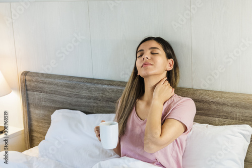 Woman sitting on bed drinking coffee smiling