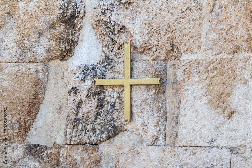 A large gilded cross hanging on the wall on the ruins of a Byzantine church complex on the territory of Emmaus Nicopolis
