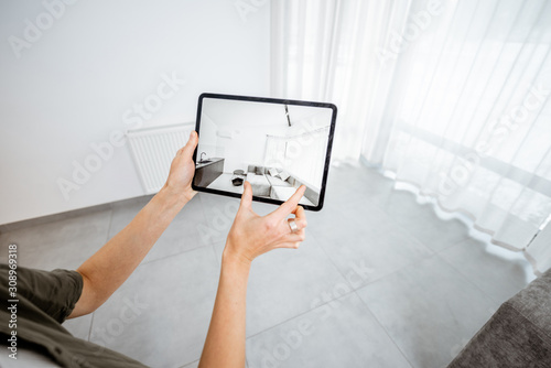 Φωτογραφία Placing new furniture on a digital tablet into the empty interior, looking how it looks before buying