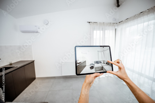 Placing new furniture on a digital tablet into the empty interior, looking how it looks before buying. Concept of augmented reality in design and retail business photo