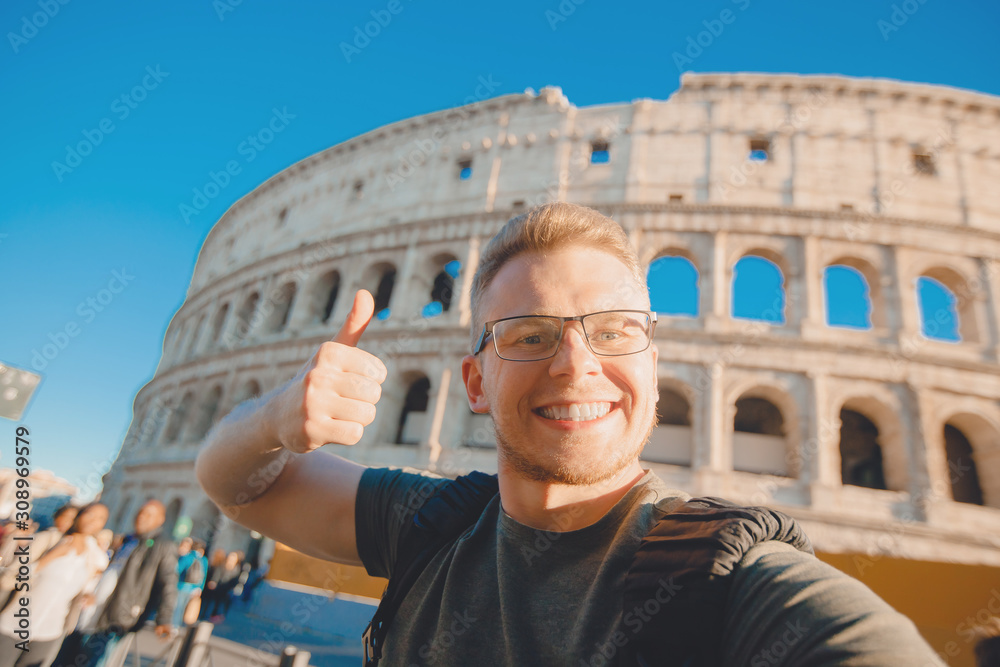 Happy caucasian man tourist with backpack taking selfie photo Colosseum in Rome, Italy. Travel trip concept