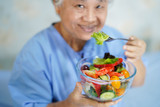 Asian senior or elderly old lady woman patient eating breakfast healthy salad food with hope and happy while sitting and hungry on bed in hospital..