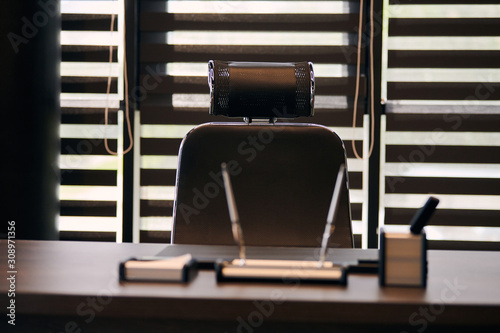Business office workplace. Work place for chief, boss or other employees. Table and comfortable chair. Light through the half open blinds