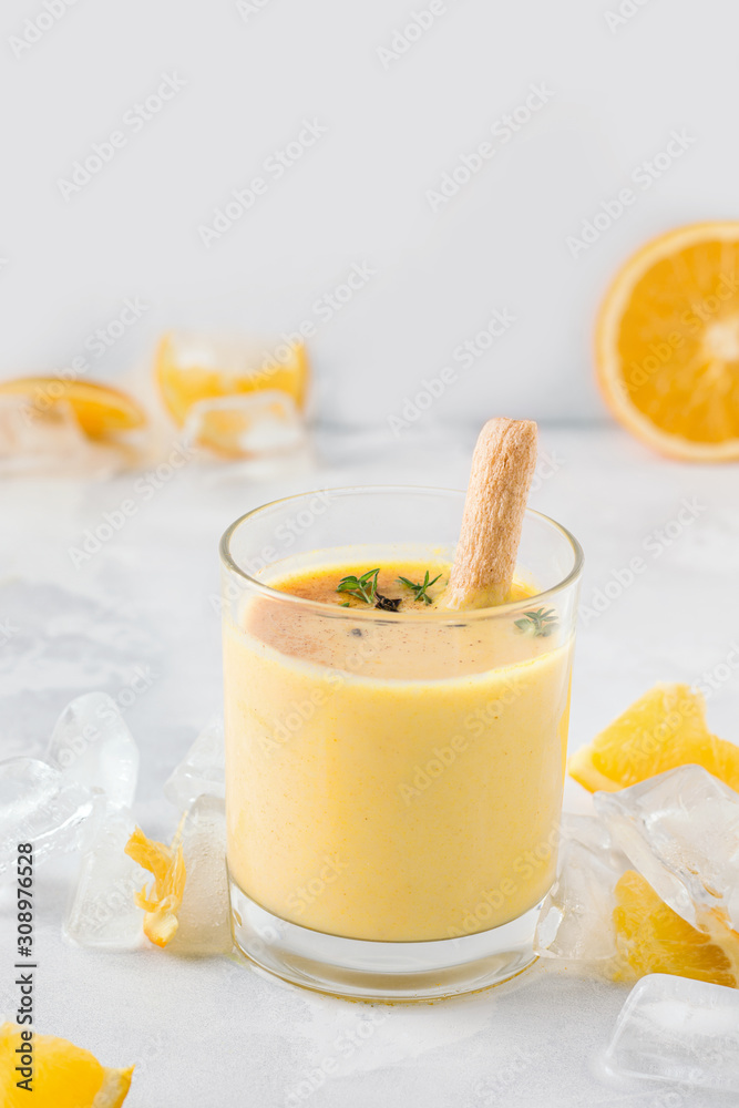 lassi drink mango close-up on a light concrete background next to a slice of orange and ice. traditional indian drink lassi drink mango close-up on a light concrete background next to a slice of orange and ice. traditional indian drink