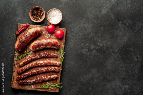 different fried sausages with spices and rosemary, on a stone table, ready to eat with copy space for your text