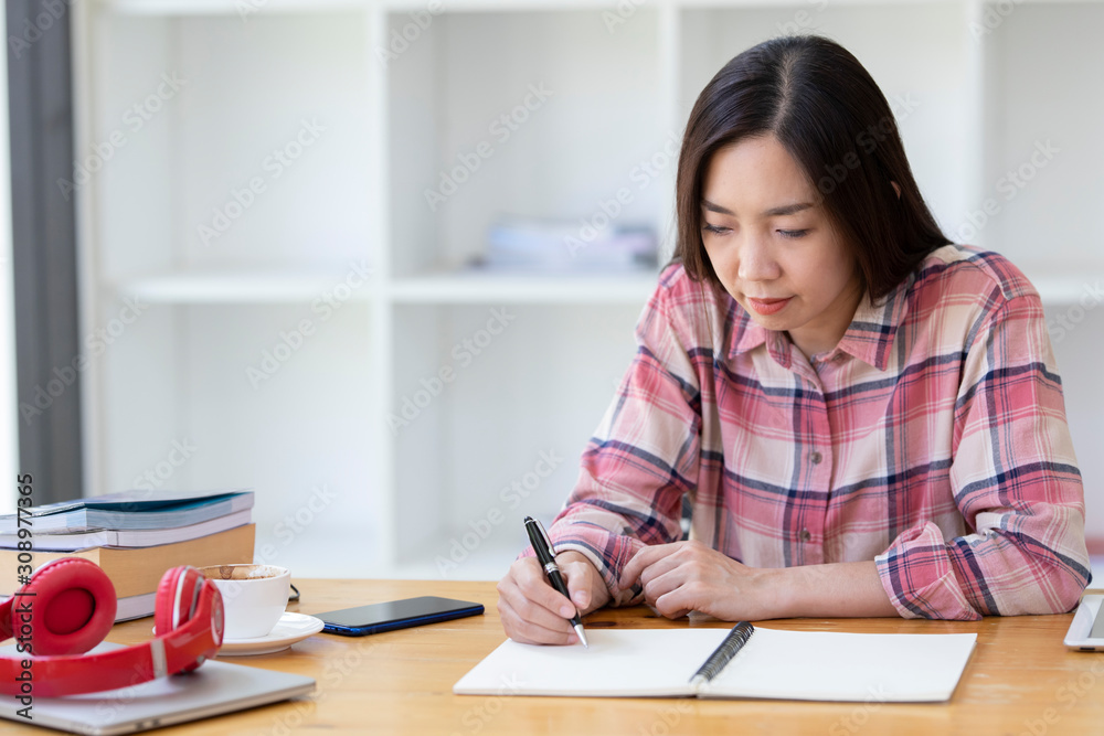 Asian woman writing something in her notebook. business women hand writing something on her paper note. Asian woman writing something in her notebook. business women hand writing something on her paper note.