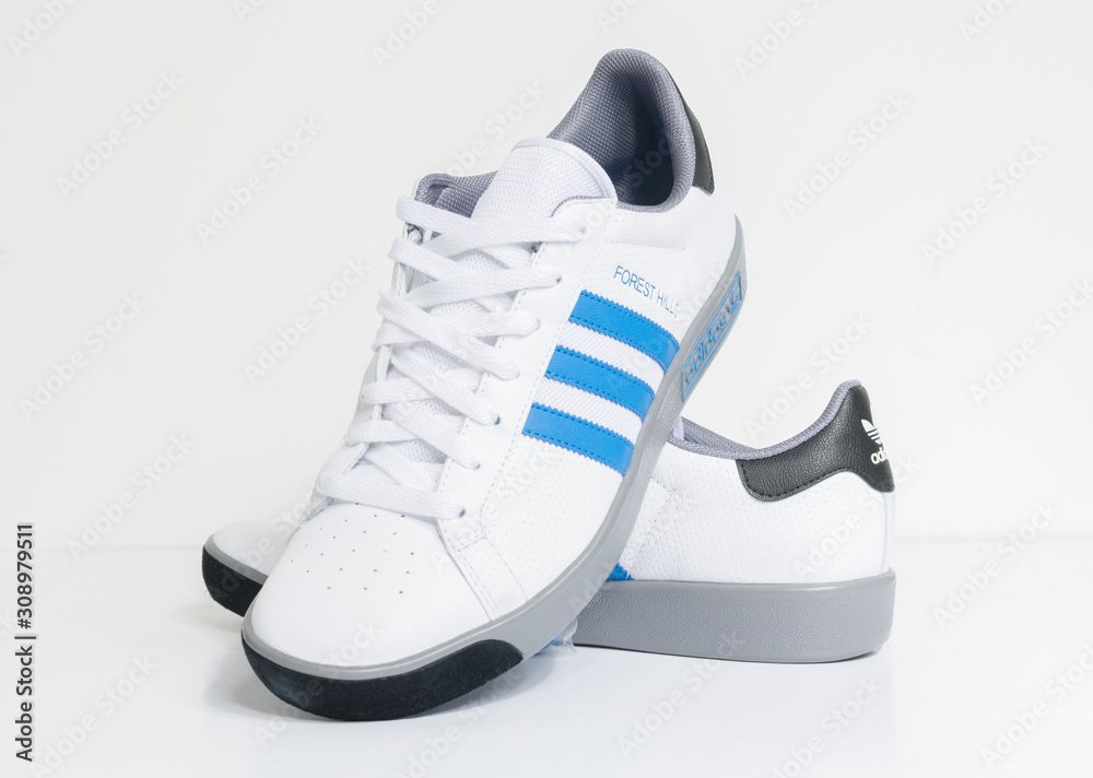 london, england, 05/05/2018 Adidas Forest Hills White grey and blue vintage sneaker trainers. Blue stripe adidas trainers, stylish retro football street fashion. famous three stripes фотография Stock