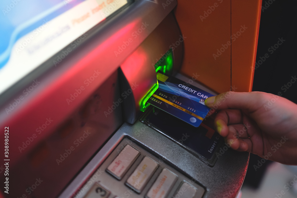 Close-up of woman Using Credit Card To Withdrawing Money From Atm Machine.