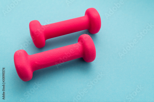 Pink dumbbells on blue background.Sports, fitness and healthy lifestyle concept.