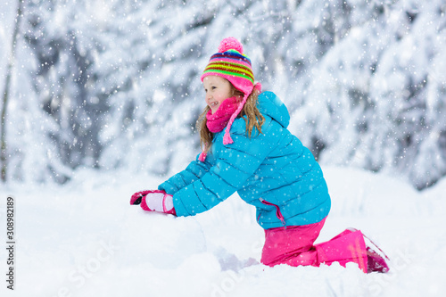 Child making snowman. Kids play in snow in winter © famveldman