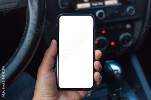 Close-up of male hand holding smartphone with mockup in the car.