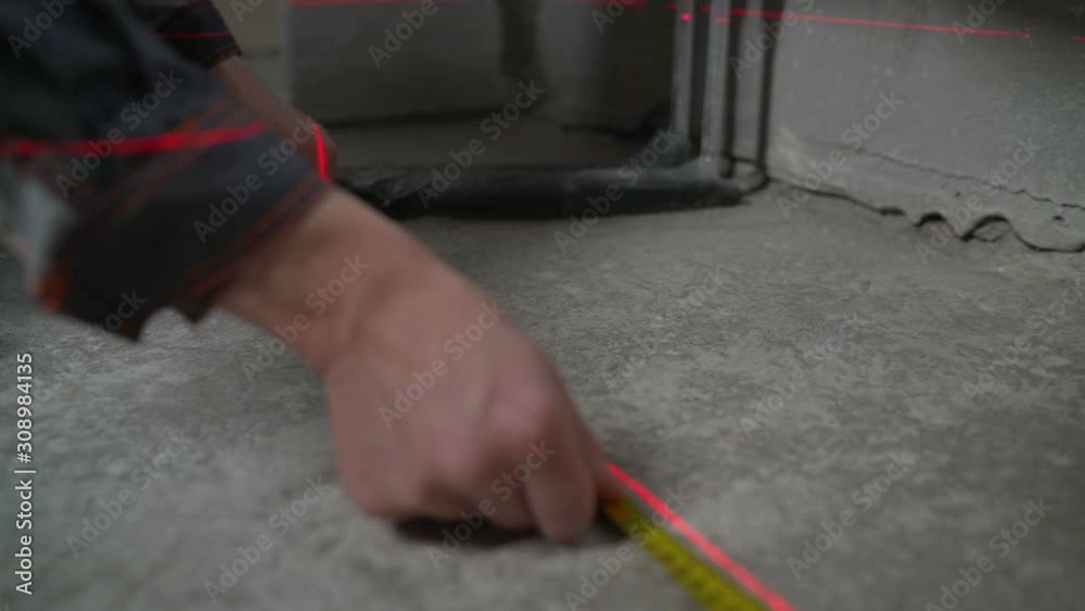 Worker puts marks on the concrete floor. Surface preparation for further application of the poured floor Worker puts marks on the concrete floor. Surface preparation for further application of the poured floor