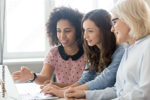 Female employees working together explain ideas on laptop
