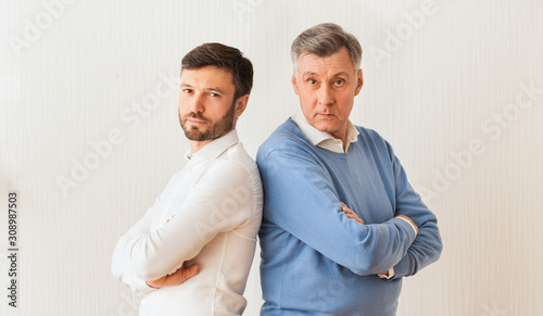 Adult Son And Senior Father Standing Crossing Hands Indoor
