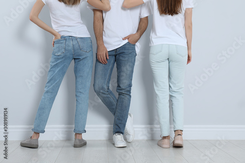 Group of young people in stylish jeans near light wall, closeup © New Africa