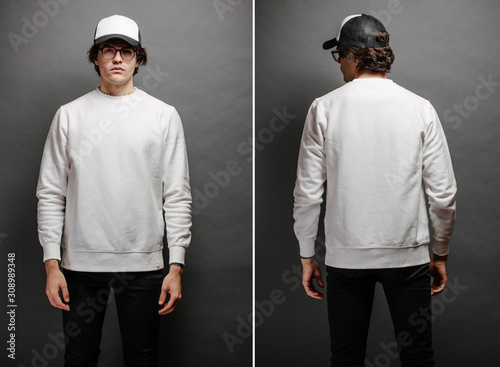 Man wearing blank white sweatshirt and empty baseball cap standing over gray background. Sweatshirt or hoodie for mock up, logo designs or design print with with free space. photo