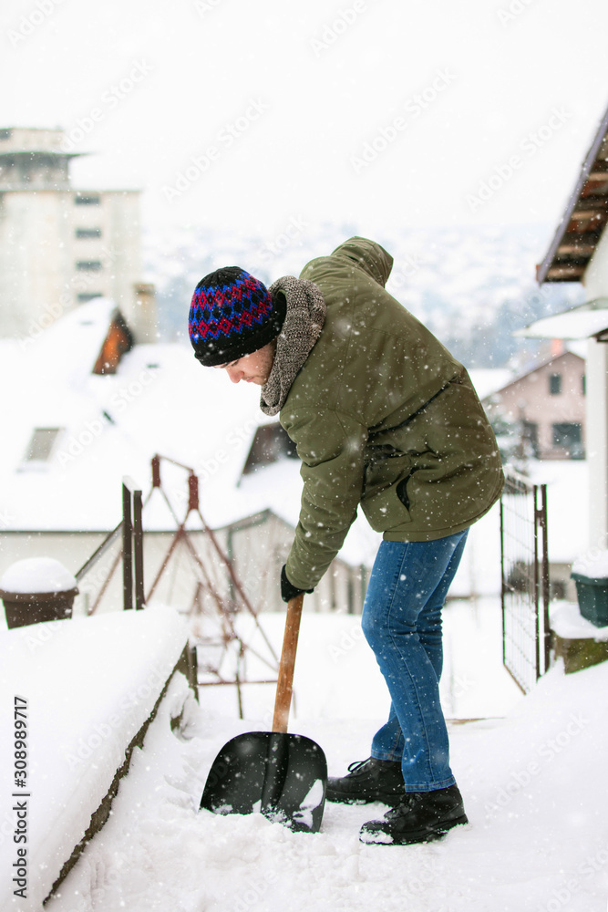 Man with shovel cleaning snow at day light in his backyard Man with shovel cleaning snow at day light in his backyard