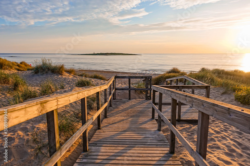 Wooden path at Baltic sea over sand dunes with ocean view  sunset summer evening