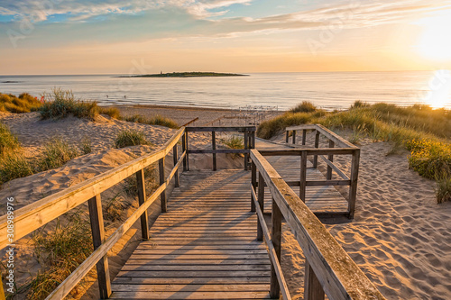 Wooden path at Baltic sea over sand dunes with ocean view, sunset summer evening