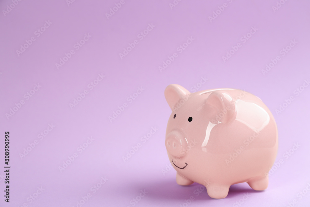 Piggy bank on violet background. Space for text