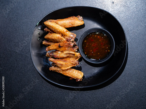 Fried chicken wings with fish sauce  On a black plate