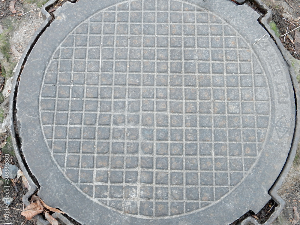 old cast iron manhole cover on bare ground old cast iron manhole cover on bare ground