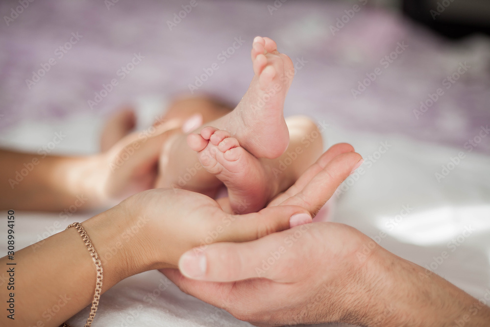 Closeup mother and father holds little baby girls legs in arms. Motherhood. Closeup mother and father holds little baby girls legs in arms. Motherhood.
