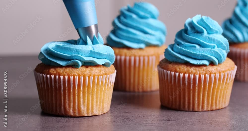 Decorating of cupcake with delicious cream on table, closeup
