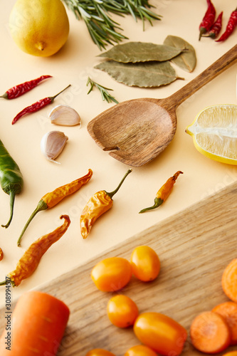 Fototapeta Naklejka Na Ścianę i Meble -  Selective focus of organic vegetables on cutting board and chili peppers on beige background