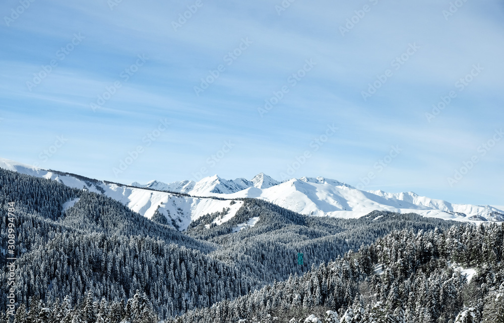 Winter snow-covered forest in the mountains. Snow-capped mountain peaks of the Caucasus mountain range near the resort of Arkhyz. Mountain peaks covered with snow in winter. Winter landscape.