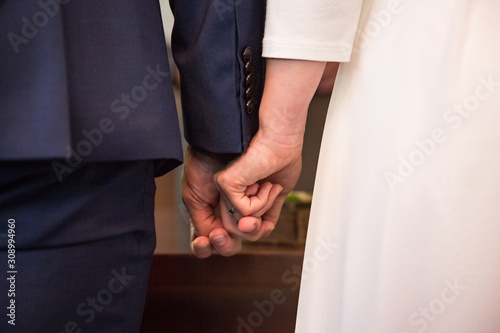 Braut und Bräutigam halten sich an den Händen während der Trauung