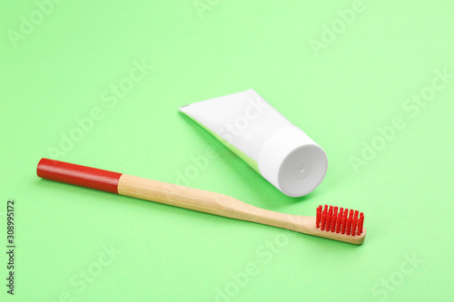 Natural bamboo toothbrush and paste on green background