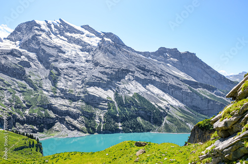 Beautiful Oeschinensee lake near Kandersteg in Switzerland. Turquoise lake surrounded by steep snow-capped mountains. Popular tourist attraction in the Swiss Alps. Summer Alpine landscape