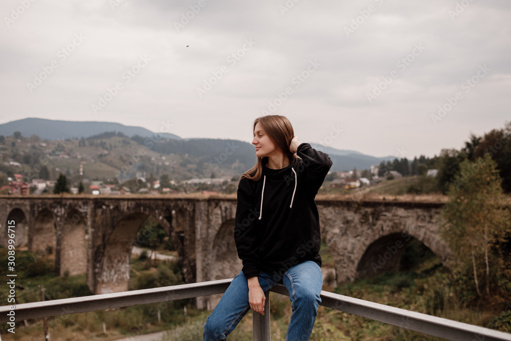 Woman tourist enjoys traveling to historical places in Ukraine, viaduct in the mountain resort village of Vorokhta, Carpathians.