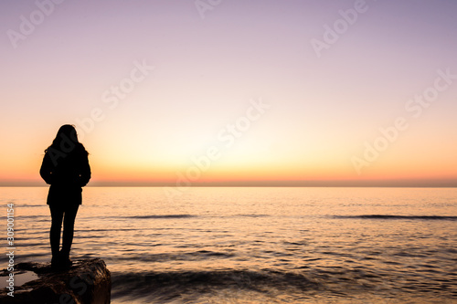 girl watching the sunrise on the beach of Oropesa, Valencia, Spain