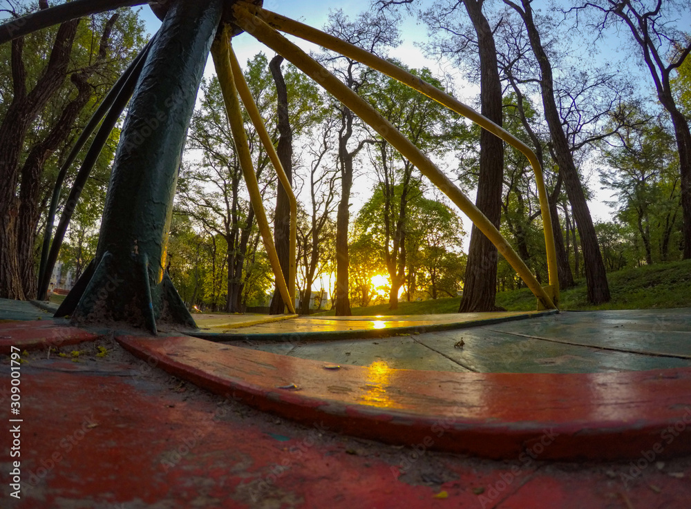 Wide angle POV shot of merry-go-round at the playground. Point-of-view from the wooden floor.
