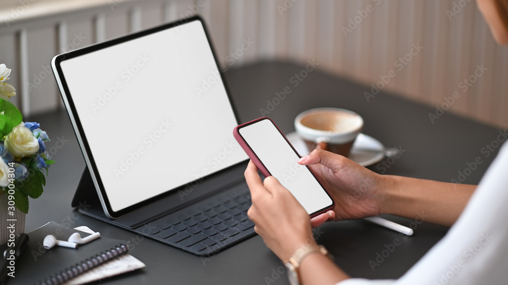 Closeup female using mockup smartphone on office workspace. Closeup female using mockup smartphone on office workspace.