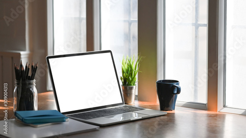 Mockup laptop computer and office supplies with coffee on wooden table.