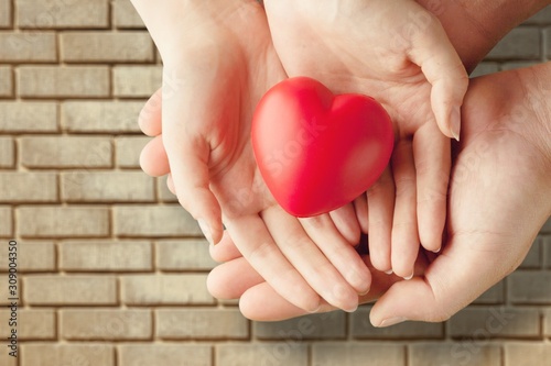 Man and woman holding red heart on background