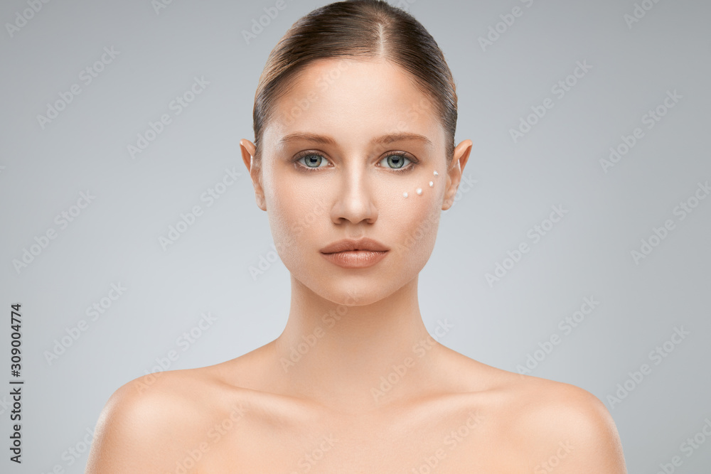 Beautiful caucasian brunette posing in studio with creme on face while looking at camera. Beautiful caucasian brunette posing in studio with creme on face while looking at camera.